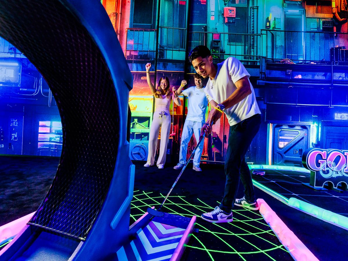 Vrienden spelen neonminigolf op een levendige indoor blacklightbaan.